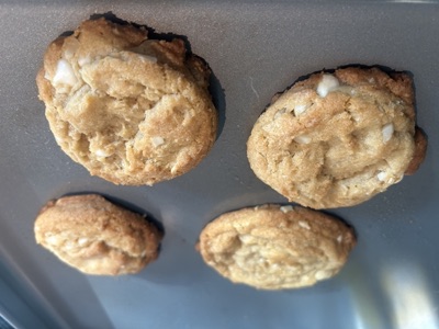 Four white chocolate macadamia cookies, fresh from the tray